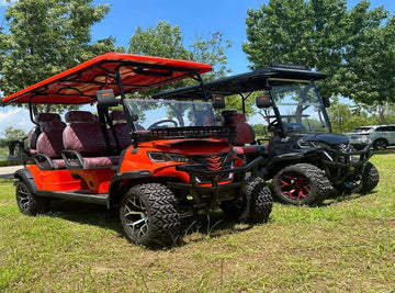 6-seater electric golf carts in vibrant colors parked on grass with trees in the background.
